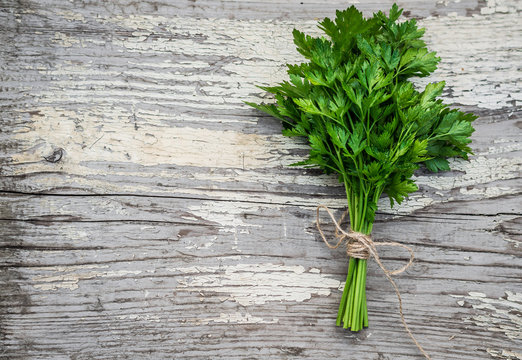 a bunch of parsley on white wooden background