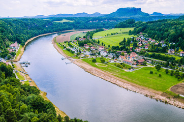 Small village and Elbe river band in front of Bastei sandstone rocks in Saxon Switzerland, Dresden, Germany