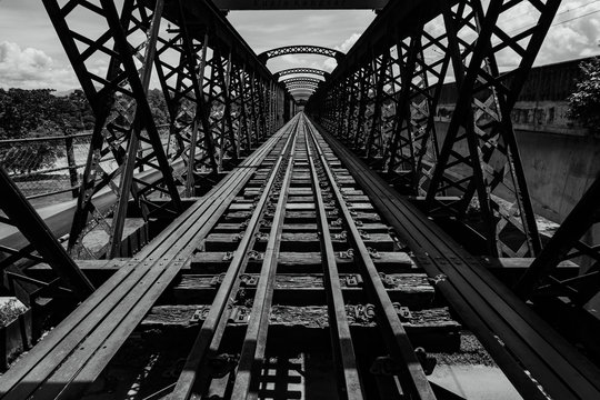 Fototapeta greyscale image of perspective view of old railway bridge at sunny day