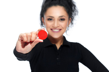 Selective focus on a red casino token in the hand of a beautiful dark haired woman copyspace gambling playing game luck offering concept.