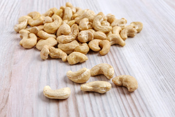 A heap of cashew nuts on a light kitchen table close-up.