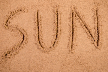 Sun written in soft wet sand on a beach
