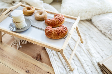 Fototapeta na wymiar Romantic breakfast in bed on a wooden tray with croissants and donuts, side view