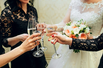 Bride and bridesmaids celebrate and drink champagne from glasses