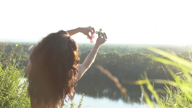 Beautiful woman balancing two fidget spinners on thumbs, slow motion.