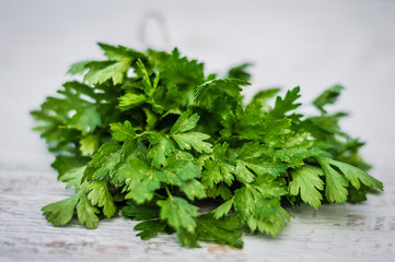 a bunch of parsley on white wooden background