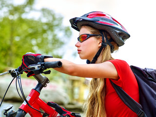 Fototapeta na wymiar Woman on bicycle ride mountain. Girl with smart watch traveling in summer park. Cycling person with rucksack counts pulse after sport training. She is in a school trip.