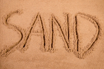 Sand written in soft wet sand on a beach