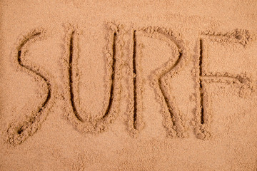 Surf written in soft wet sand on a beach