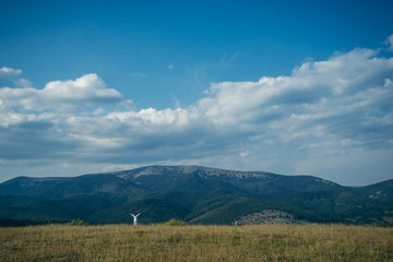 woman in field with mountains on background pictered from long distance