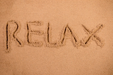 Relax written in soft wet sand on a beach