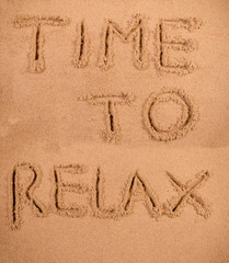 Time to relax written in soft wet sand on a beach