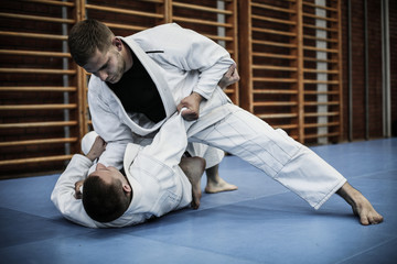 Two young males practicing judo together.