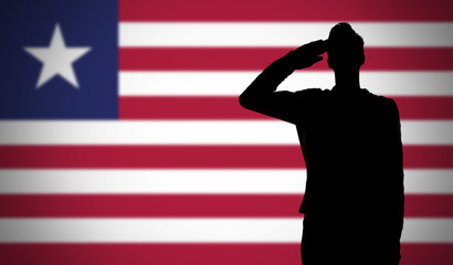 Silhouette of a soldier saluting against the liberia flag