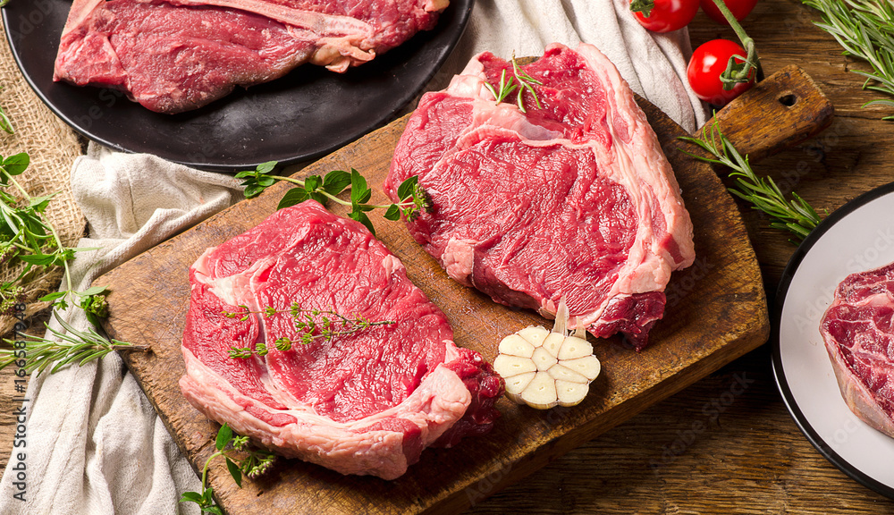 Wall mural Raw beef meat on a dark wooden board.