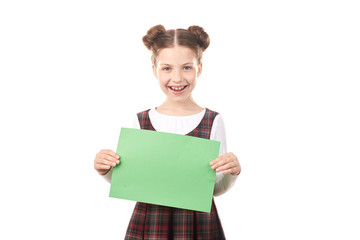 Fototapeta premium Portrait of happy girl in school uniform holding blank paper against white background