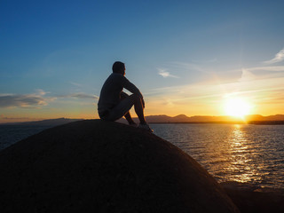 A man is watching the sunset on the coast