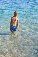 handsome child boy  splashes water on the azure sea. Children playing in azure sea. Concept of vacations and recreation at sea