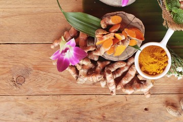 Turmeric root with turmeric powder on wood background
