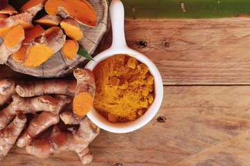 Turmeric root with turmeric powder on wood background
