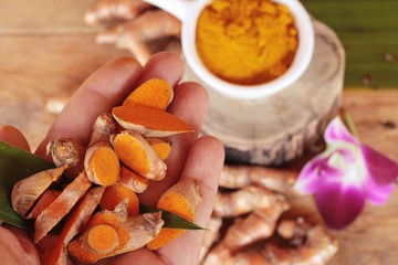 Turmeric root with turmeric powder on wood background