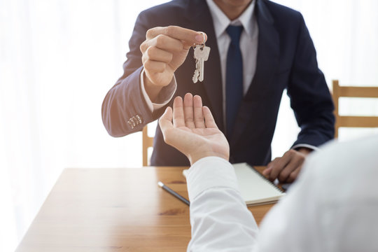 Agent Giving Keys Of New House With Customer In Office