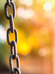 Close up of old and rust chain links on sunset blurred background