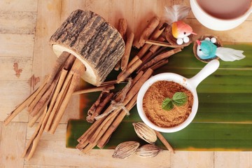 cinnamon powder and sticks on wood background