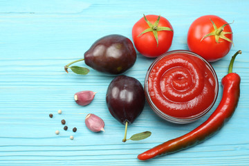 raw plum, tomato and ketchup on wooden table. top view