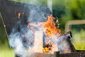 Firewood is burning in the barbeque grill in the outside