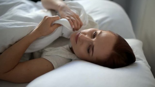 Cheerless woman lying in bed at home
