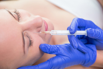 Naklejka premium Beautiful young woman gets beauty injection in eye area