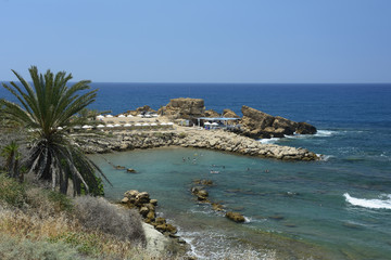 Beach by the sea with umbrellas and sunbeds and bathing people