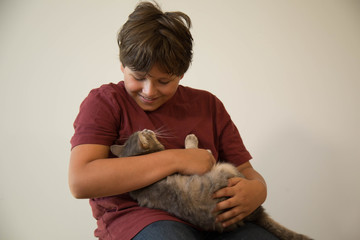 Cute caucasian teen hugging grey cat indoor isolated 