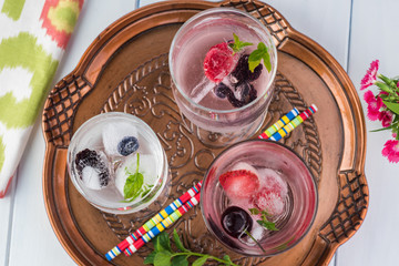 Glasses of water with ice cubes with fresh berries.