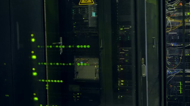 Rows of black network cabinets with see-through doors.  
