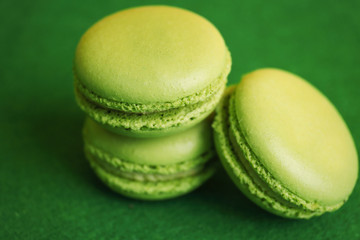 Tasty macarons on green background