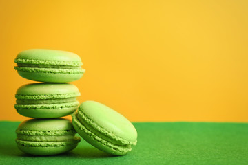 Tasty macarons on green surface against color background