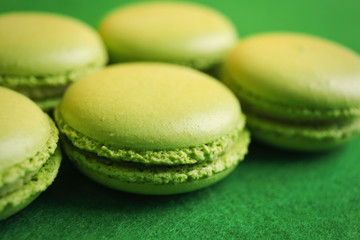 Tasty macarons on green background