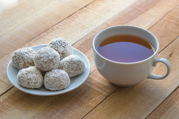 White mug with tea and cakes on the wooden table.