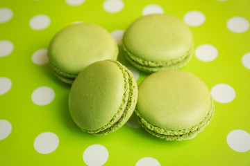 Tasty macarons on green dotted background