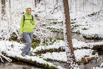 woman filling bottle of water from a winter forest stream.