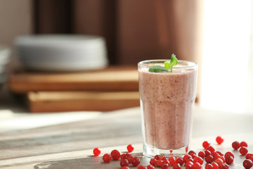 Glass with fresh berry smoothie on table
