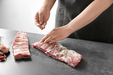 Professional cooker spicing fresh juicy spare ribs on table