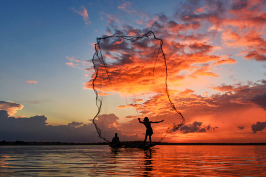 Silhouetted fisherman fishing in the river during sunset
