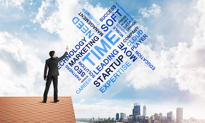 Young businessman standing on house roof and writing leadership skill concept. Mixed media
