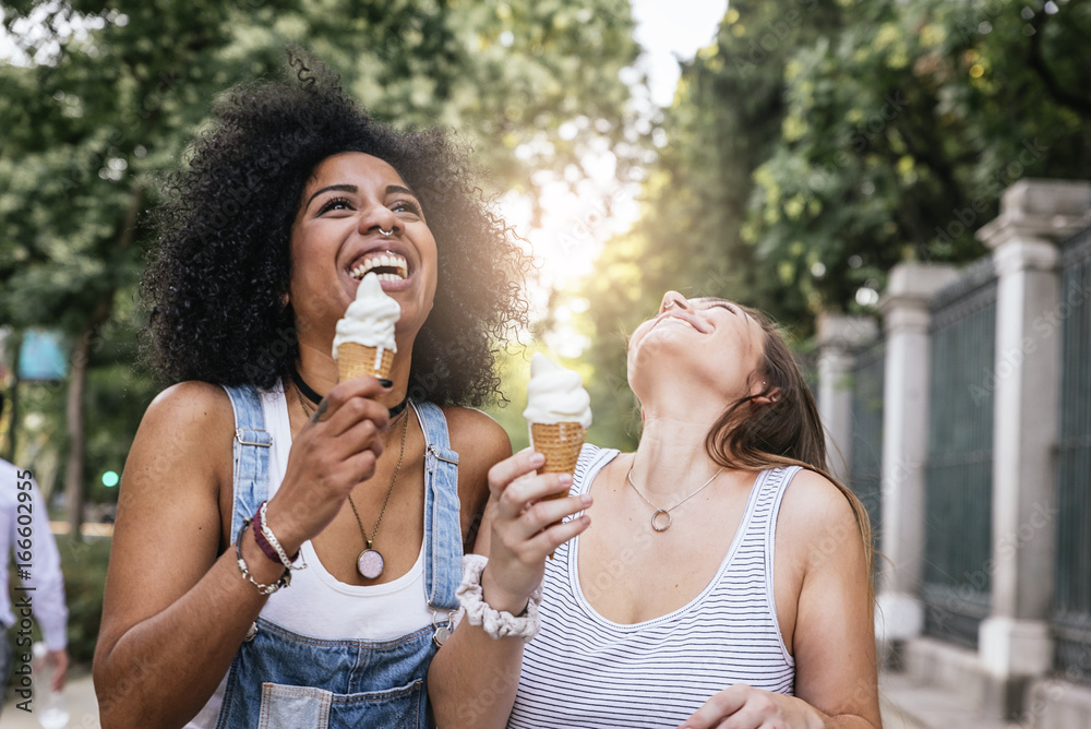 Wall mural beautiful women eating one ice cream in the street.