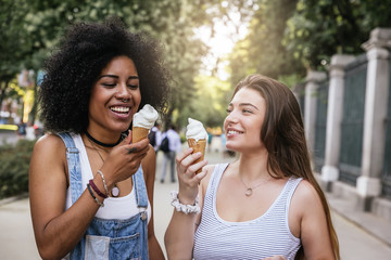 Beautiful women eating one ice cream in the street.
