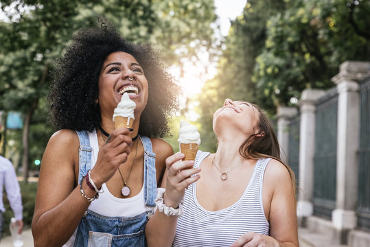Beautiful women eating one ice cream in the street.