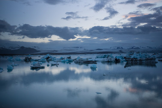 Iceland - Blue shining ice floes in glacier lagoon at midnight